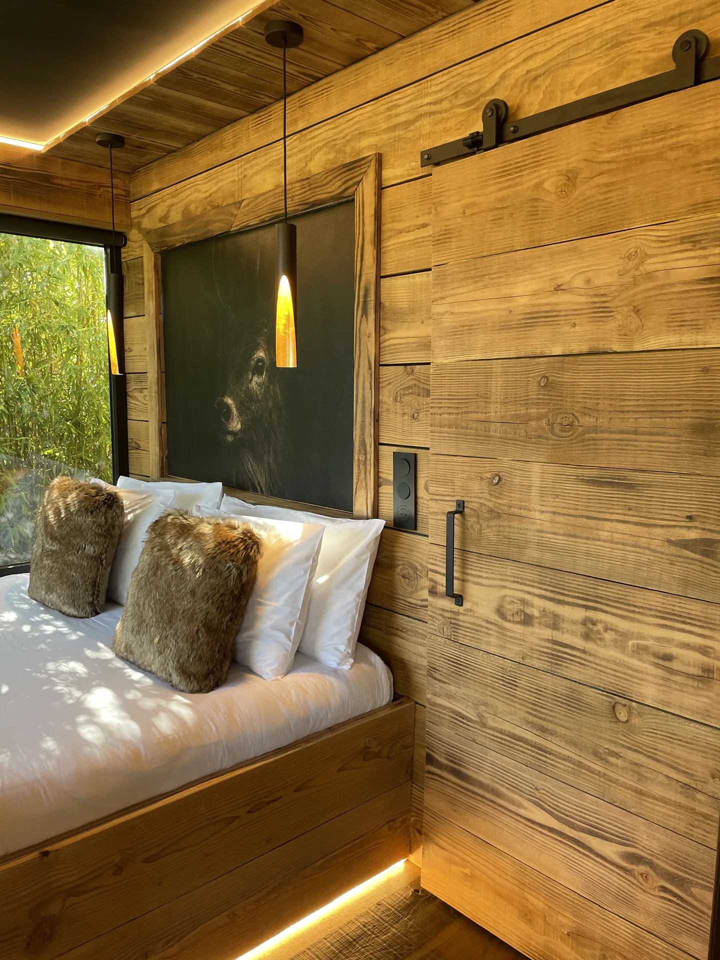 Chambre en bois massif avec porte coulissante de grange et tableau animalier au-dessus du lit